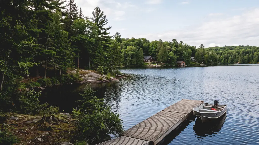 A dock and fishing boat on Drag Lake with cottages across the water in the Haliburton Highlands