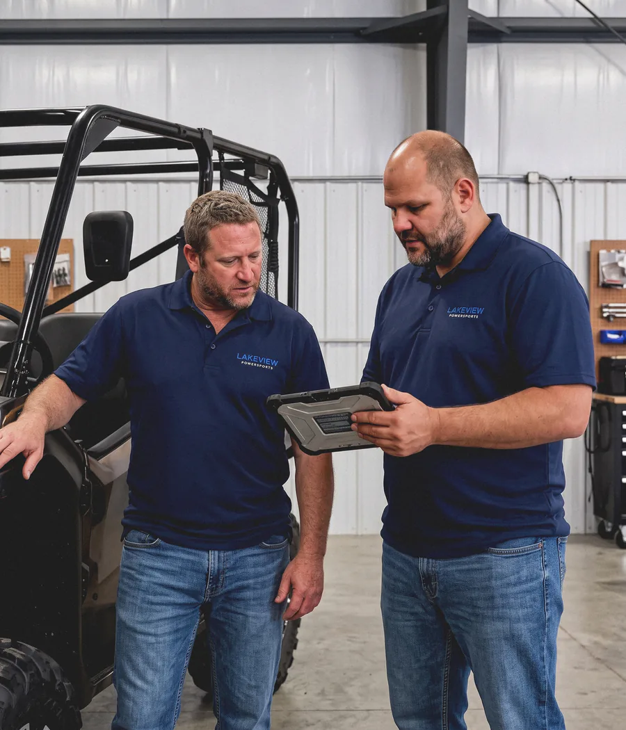 George and Marko reviewing a diagnostic tablet together beside a side-by-side in the workshop