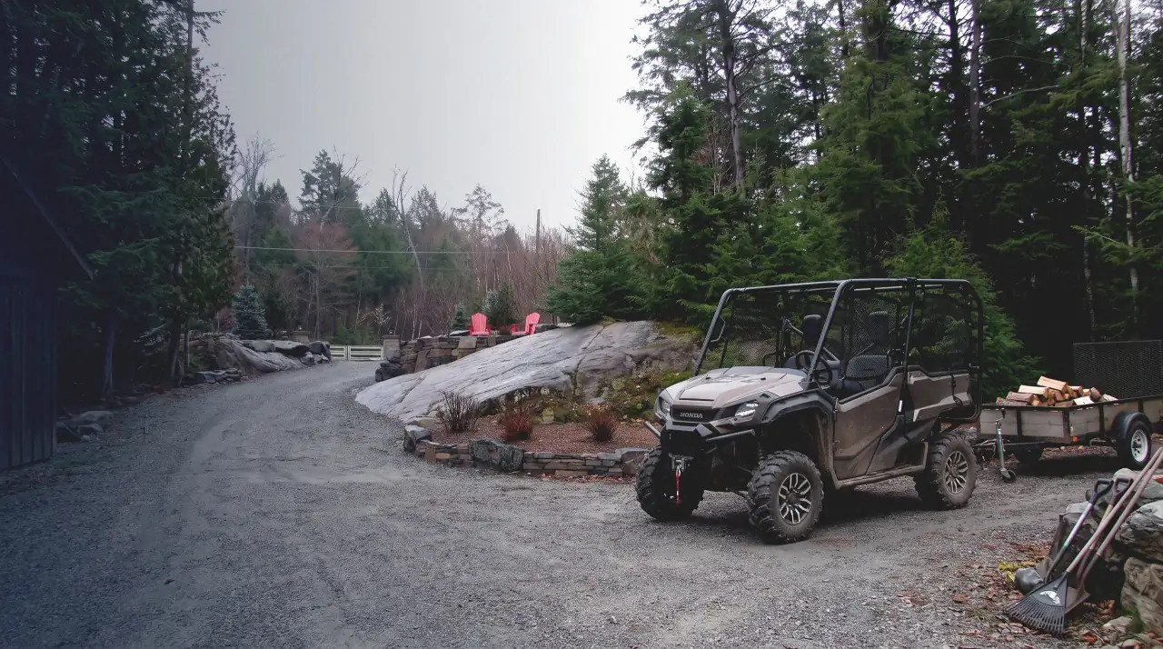 A Honda Pioneer side-by-side hitched to a firewood trailer on a Haliburton property driveway