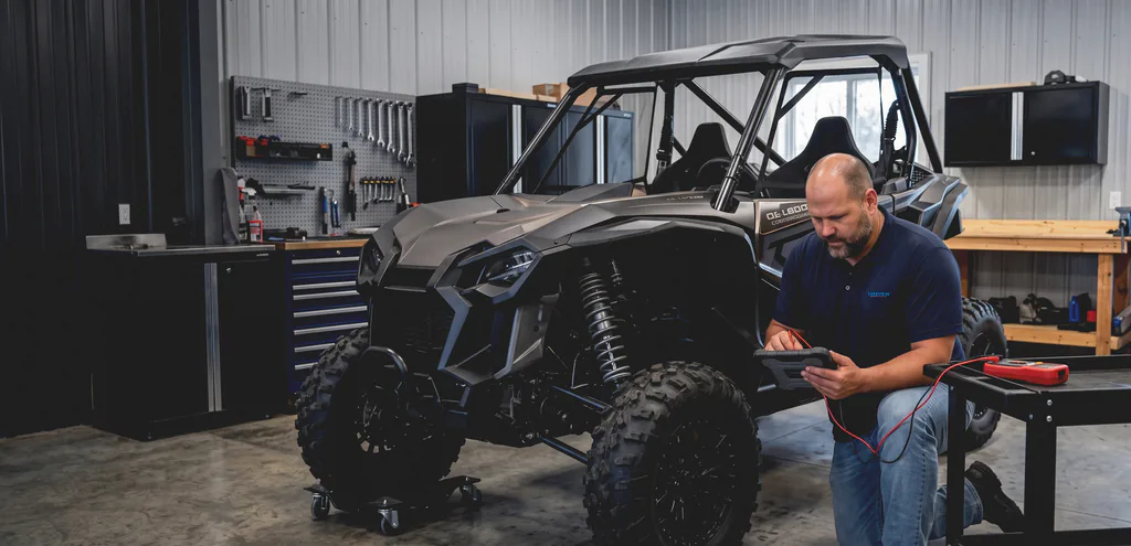 A Lakeview mechanic taking a meter reading on a Can-Am side-by-side with a diagnostic tablet in hand