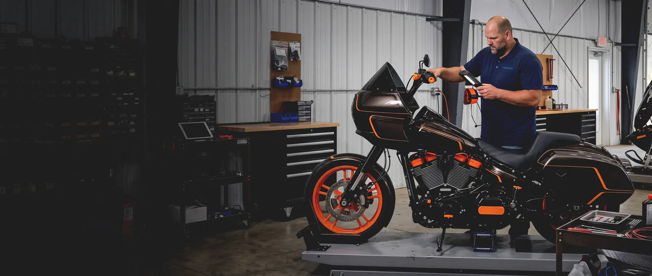 A Lakeview mechanic running a diagnostic tablet over a Harley-Davidson Road Glide raised on a motorcycle lift